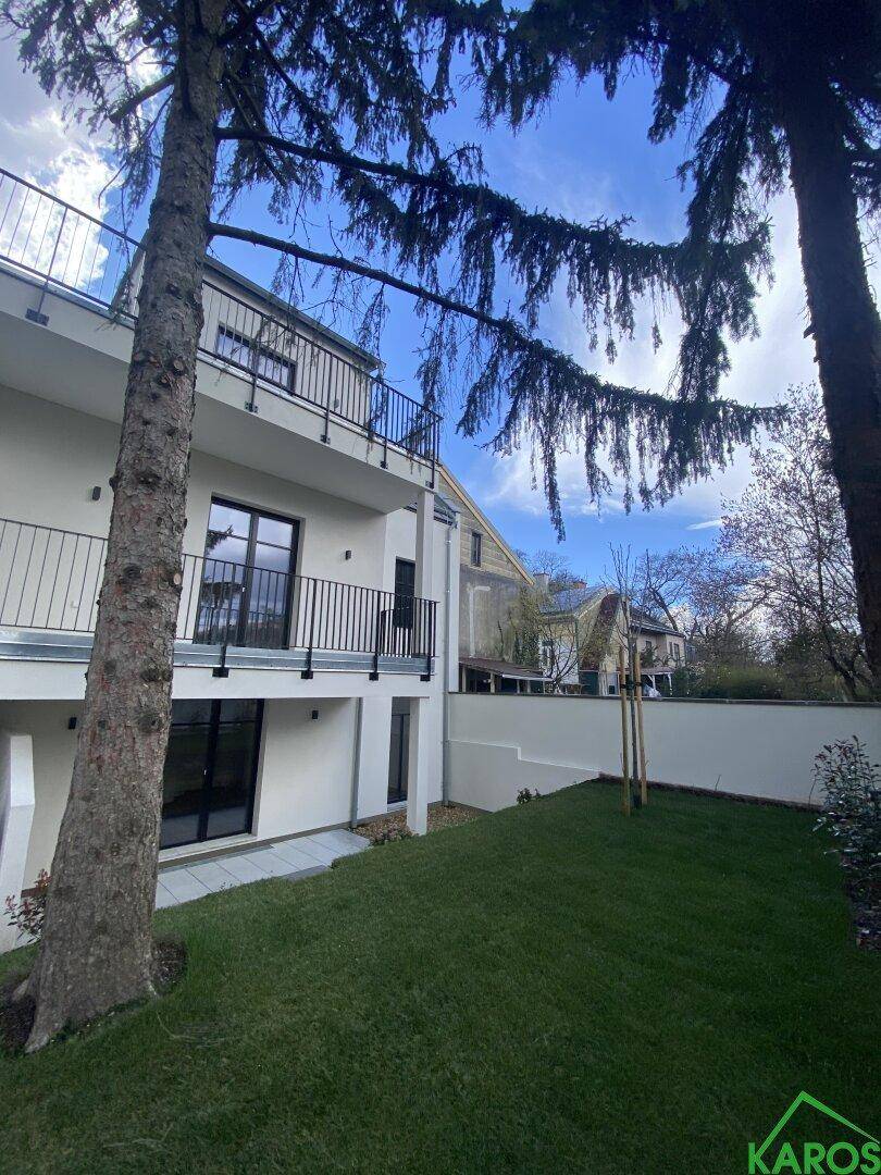 Moderne Wohnanlage mit weißer Fassade, Balkonen und einem gepflegten Rasenbereich im Freien.