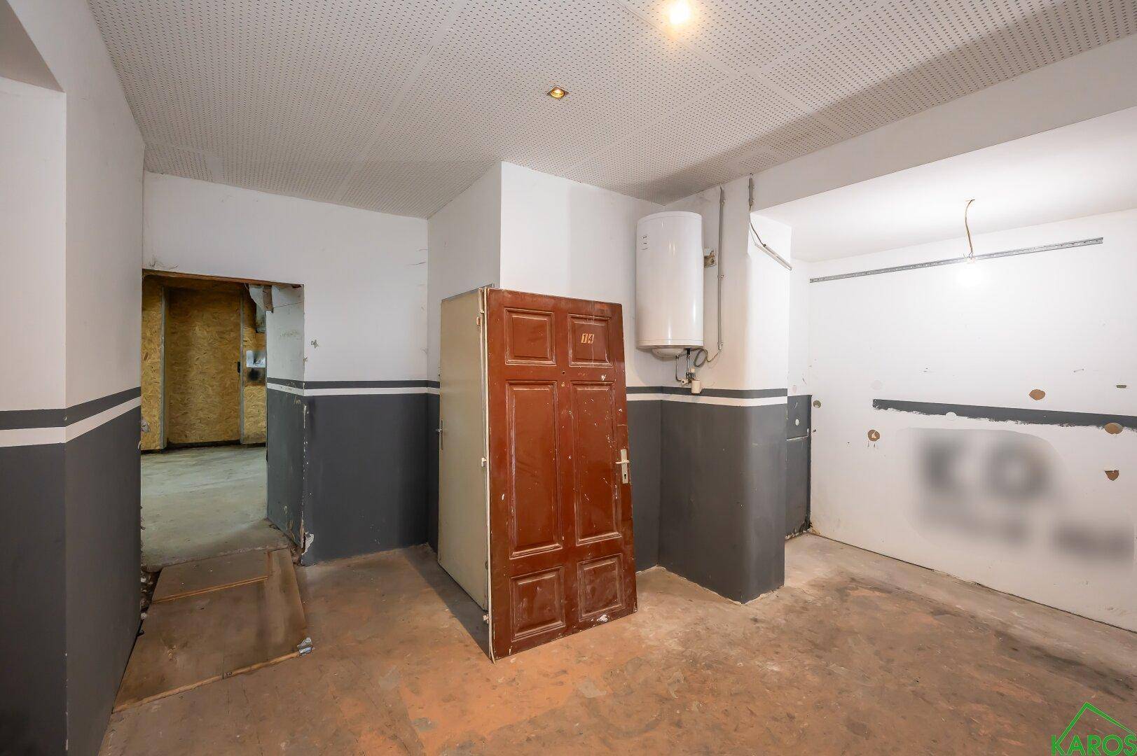 Raum mit Boiler, Betonboden und zweifarbiger Wandgestaltung, bereit für Renovierung.