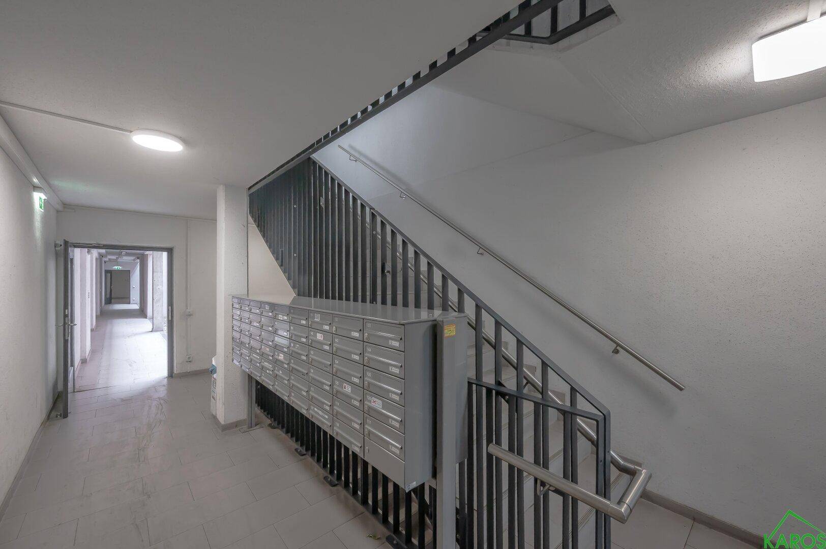 Heller Flur im Gebäude mit Treppenhaus und Briefkästen für die Bewohner.