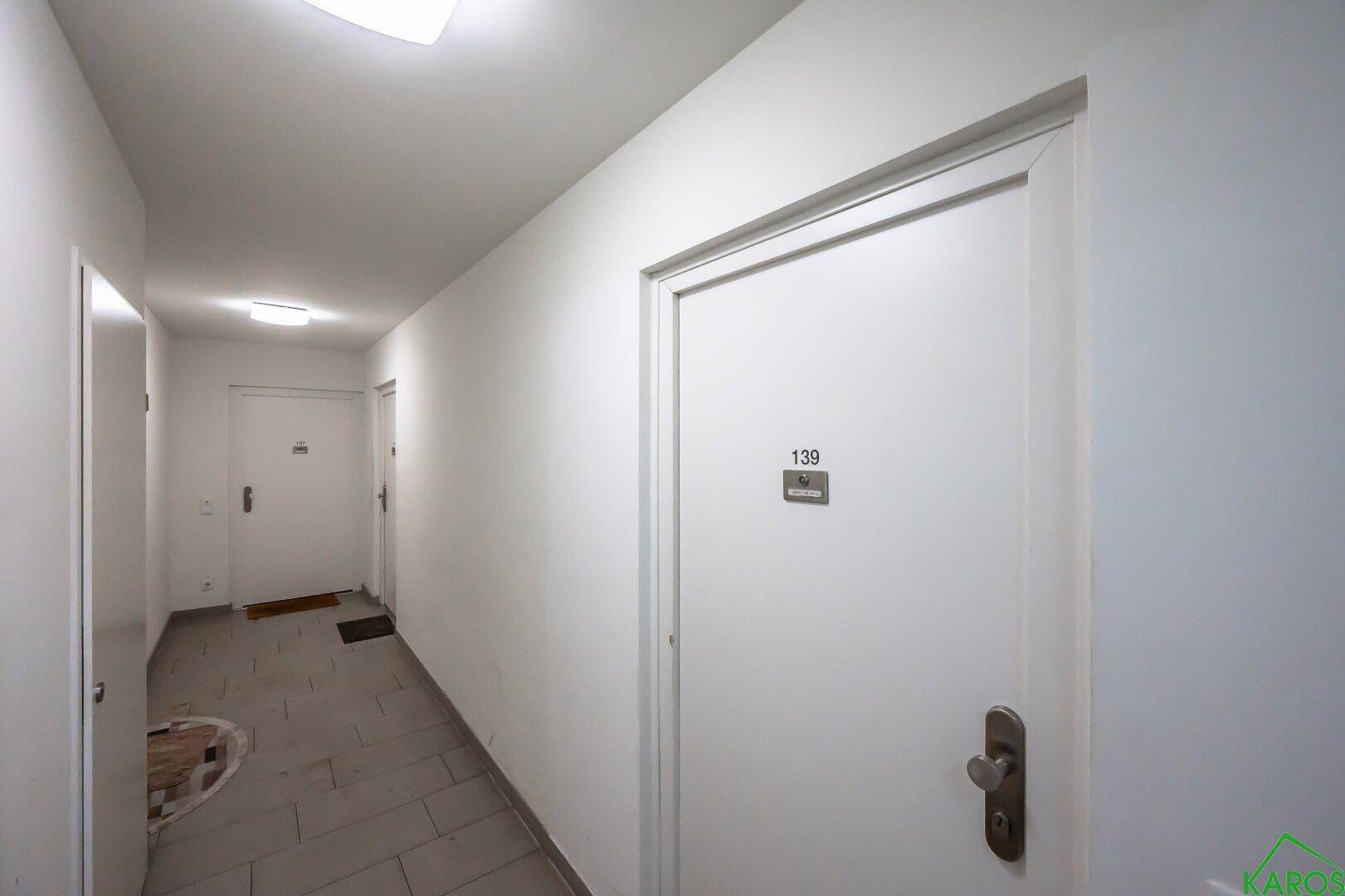 Langer, heller Flur mit mehreren Wohnungstüren und Fliesenboden.