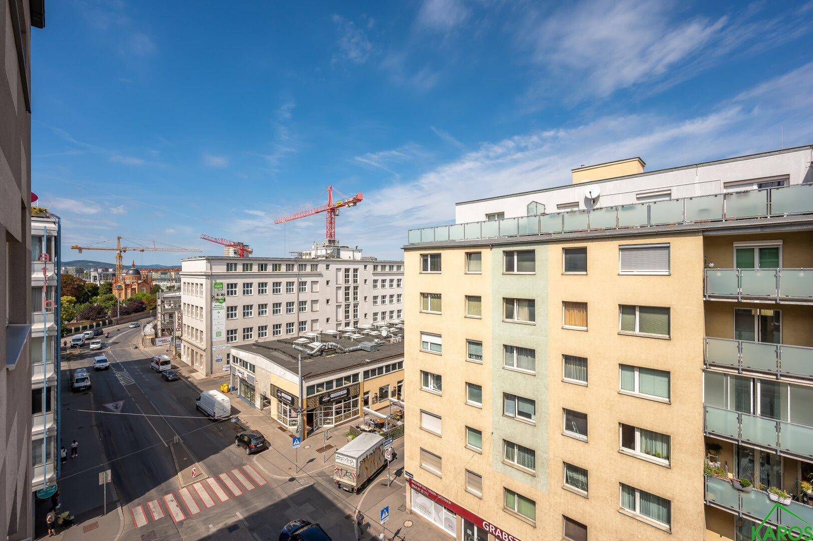 Panoramablick über die Stadt mit Gebäuden, Straßen und Baukranen am Horizont.