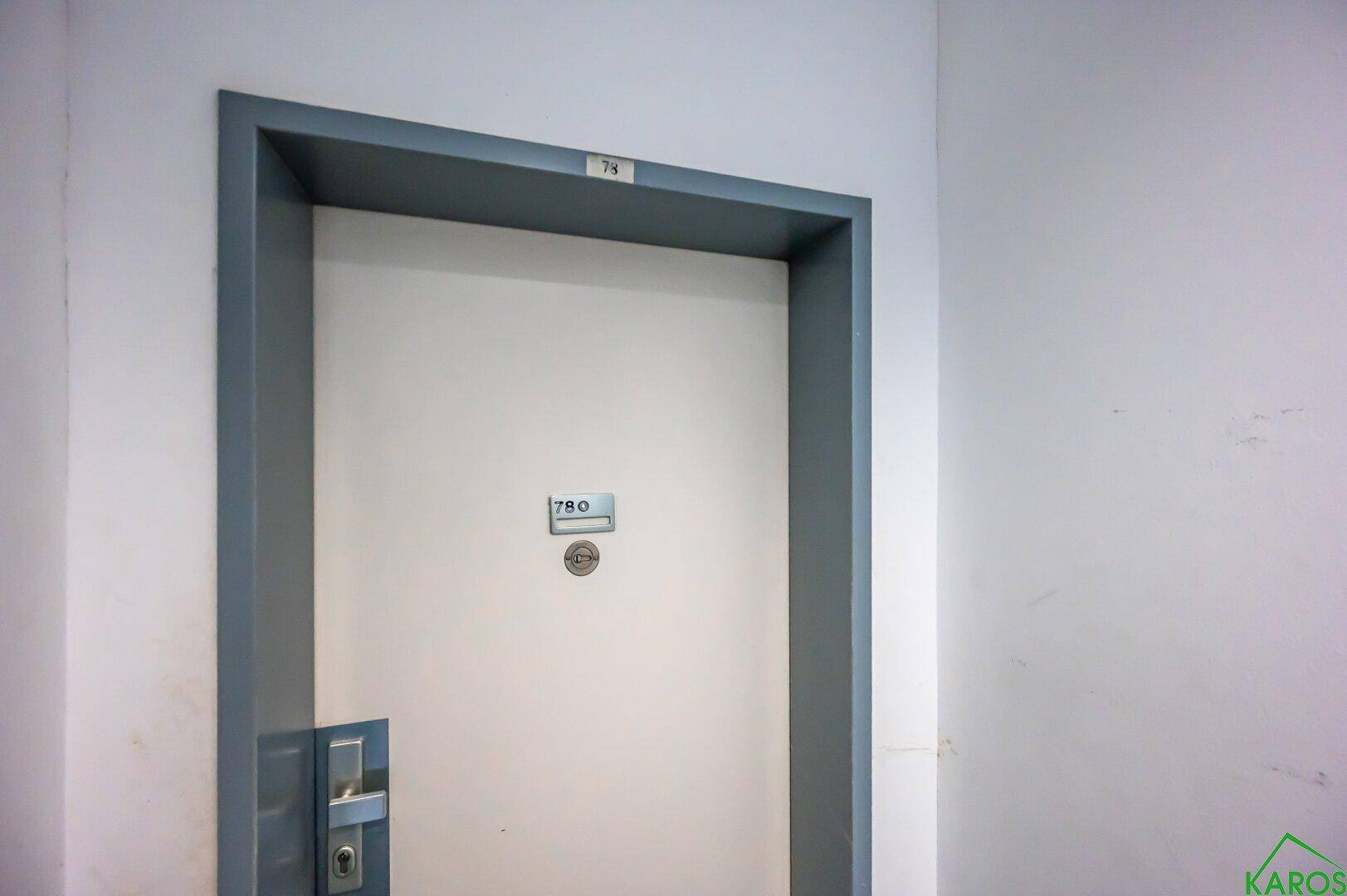 Eine weiße Wohnungstür mit der Nummer 780 in einem schlichten Flur.