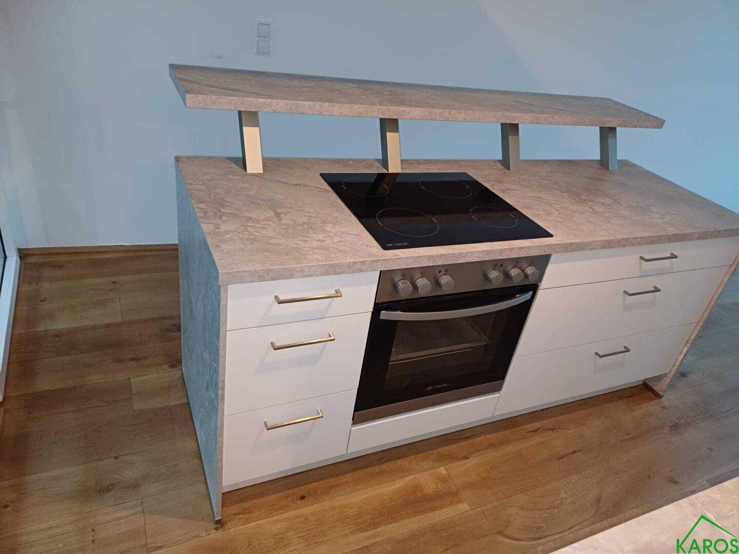 Kochinsel mit integriertem Cerankochfeld und Backofen, umgeben von Schubladen.