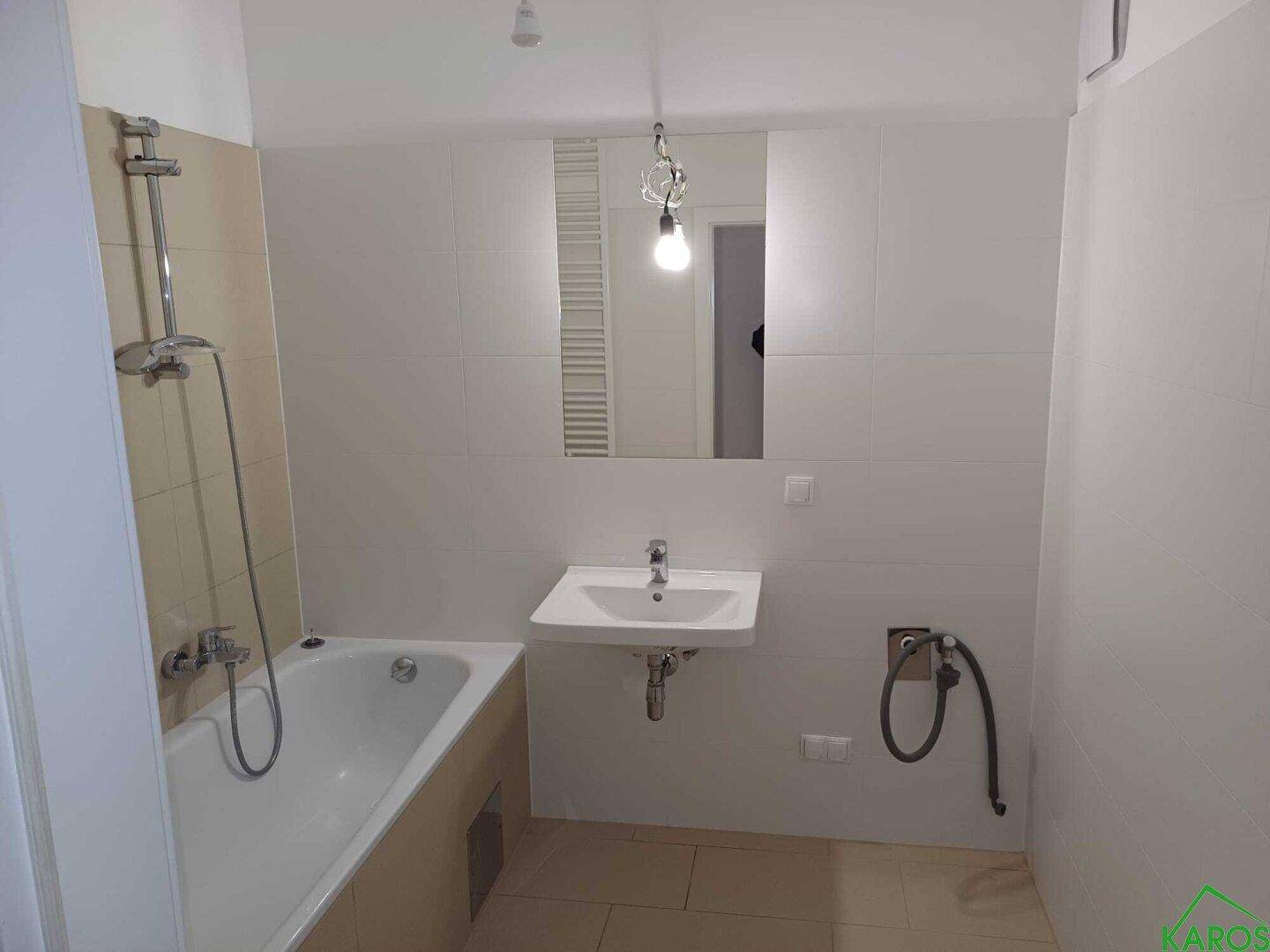 Modernes Badezimmer mit Badewanne, Waschbecken und großem Spiegel.