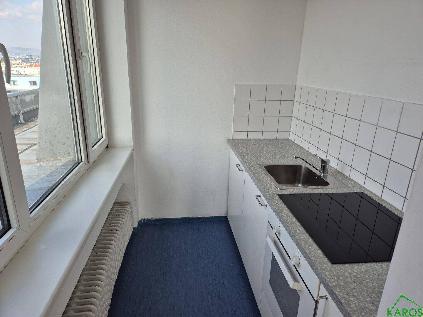 Funktionale Küche mit weißer Einrichtung, Kochfeld und Fenster mit Ausblick.
