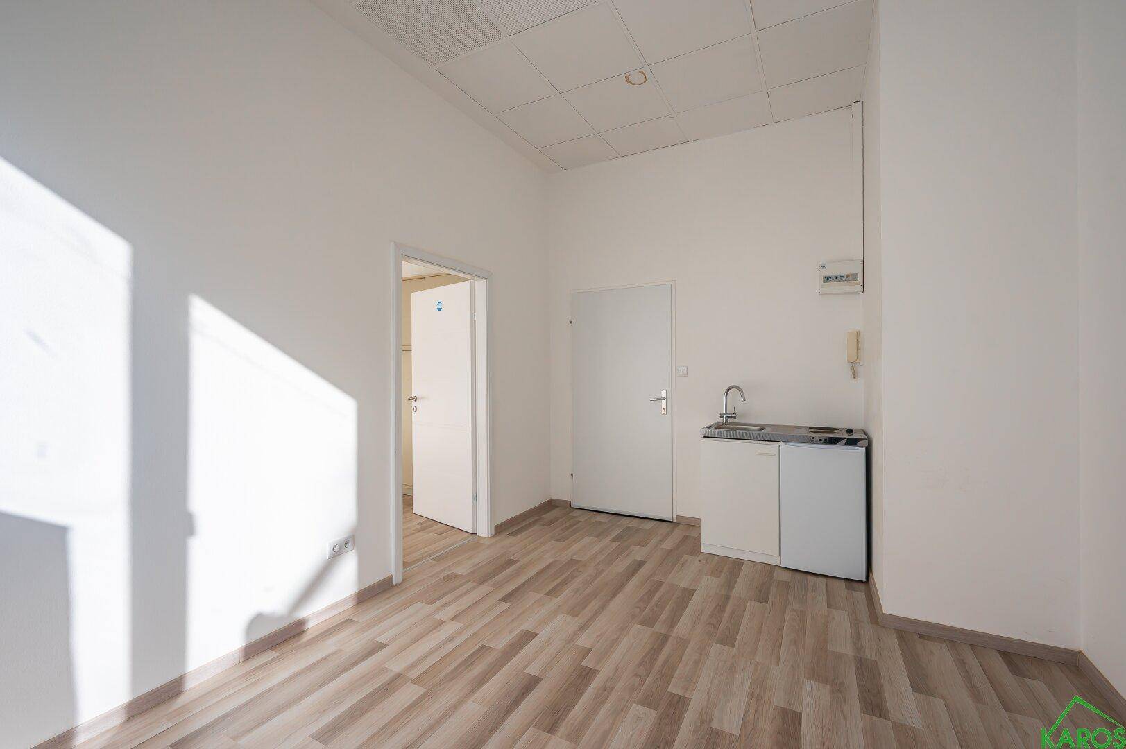 Kleiner Küchenbereich mit Spüle und Unterschrank in einem hellen Raum mit Laminatboden.