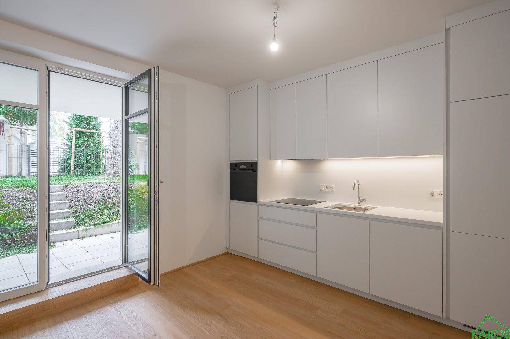 Moderne Einbauküche in Weiß mit integrierten Geräten und Zugang zum Außenbereich.
