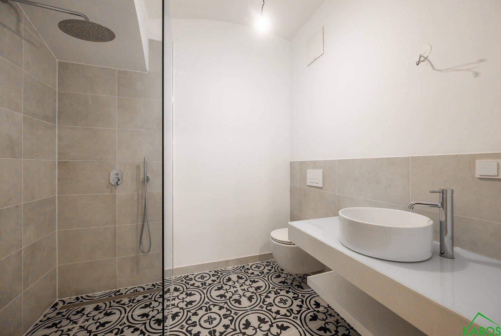 Modernes Badezimmer mit begehbarer Dusche, stilvollen Fliesen und Einzelwaschbecken.
