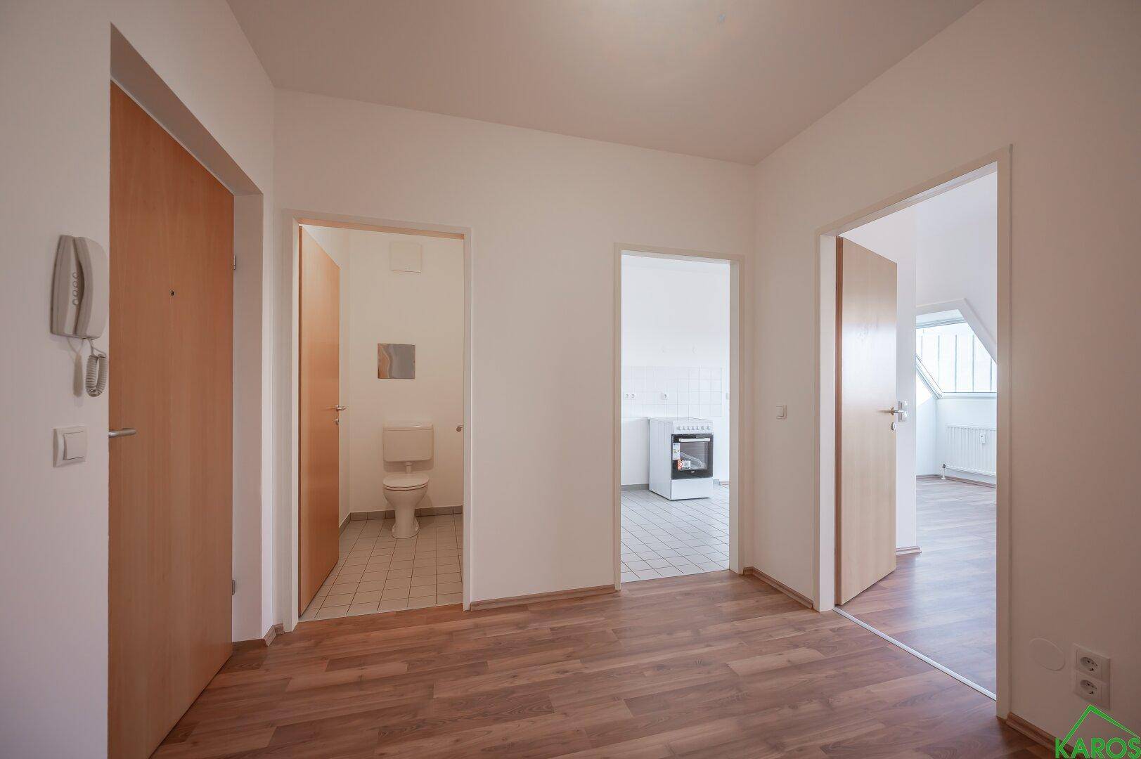 Heller Flur mit Laminatboden und Zugang zu verschiedenen Zimmern und dem WC.