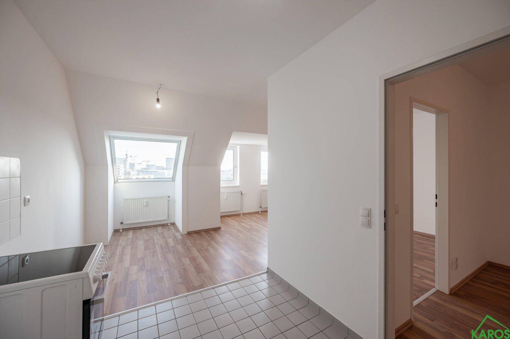 Heller Wohnbereich im Dachgeschoss mit Laminatboden und angrenzender Küchenzeile.