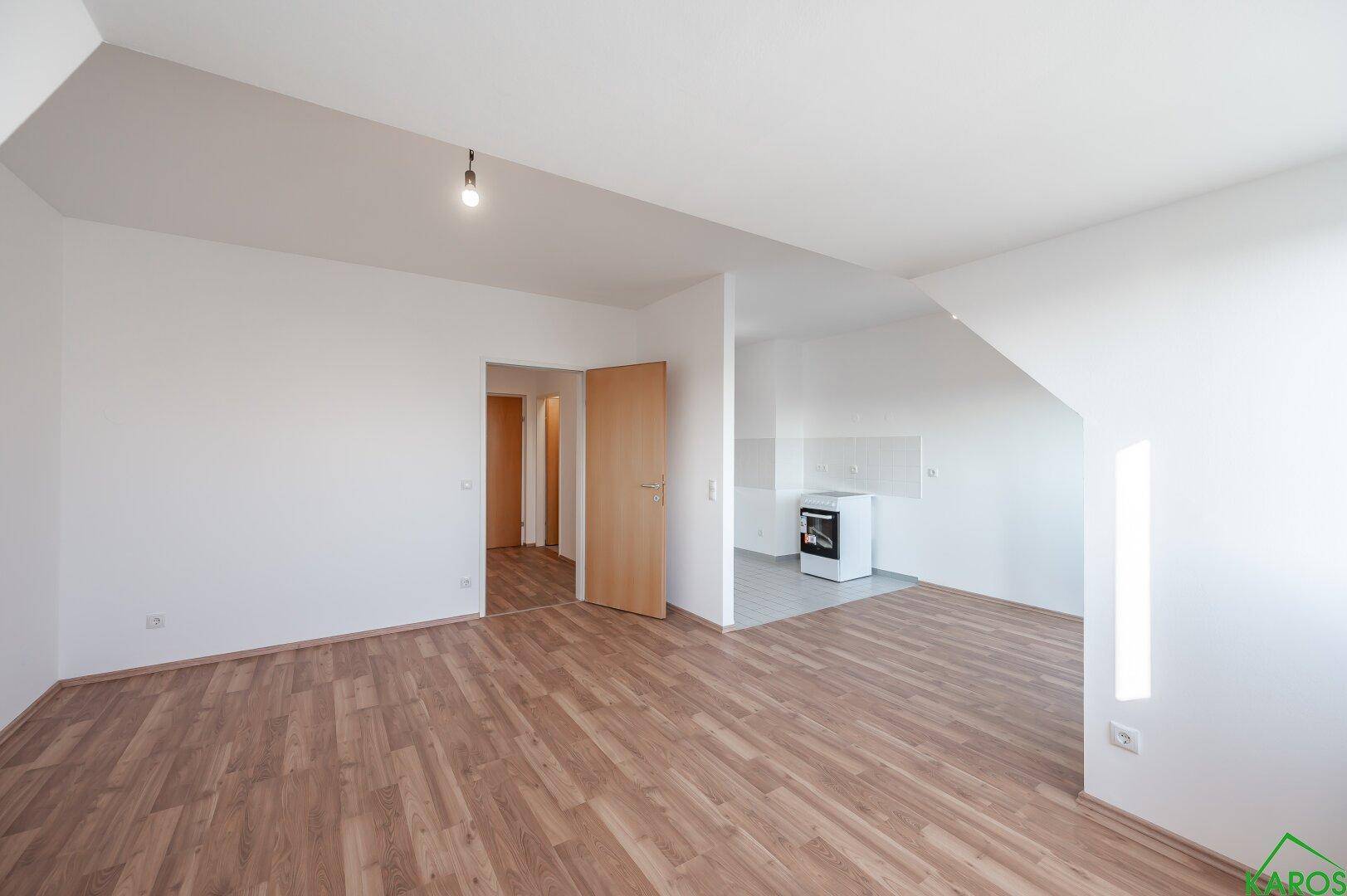 Geräumiger Wohnbereich mit Laminatboden und angrenzendem Küchenbereich.