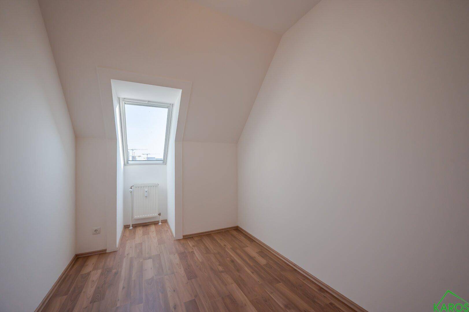 Gemütliches Dachzimmer mit Laminatboden und einem großen Dachfenster für viel Licht.