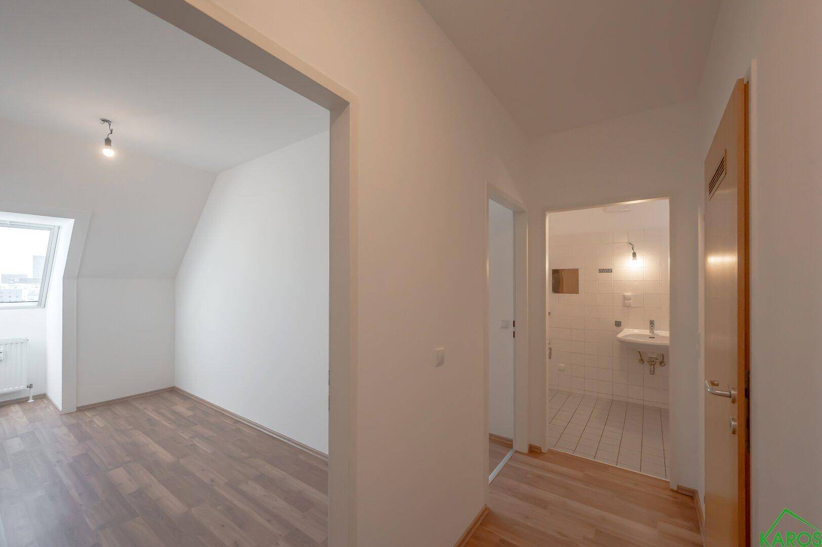 Flur mit Laminatboden, der zum Dachzimmer und einem Badezimmer führt.