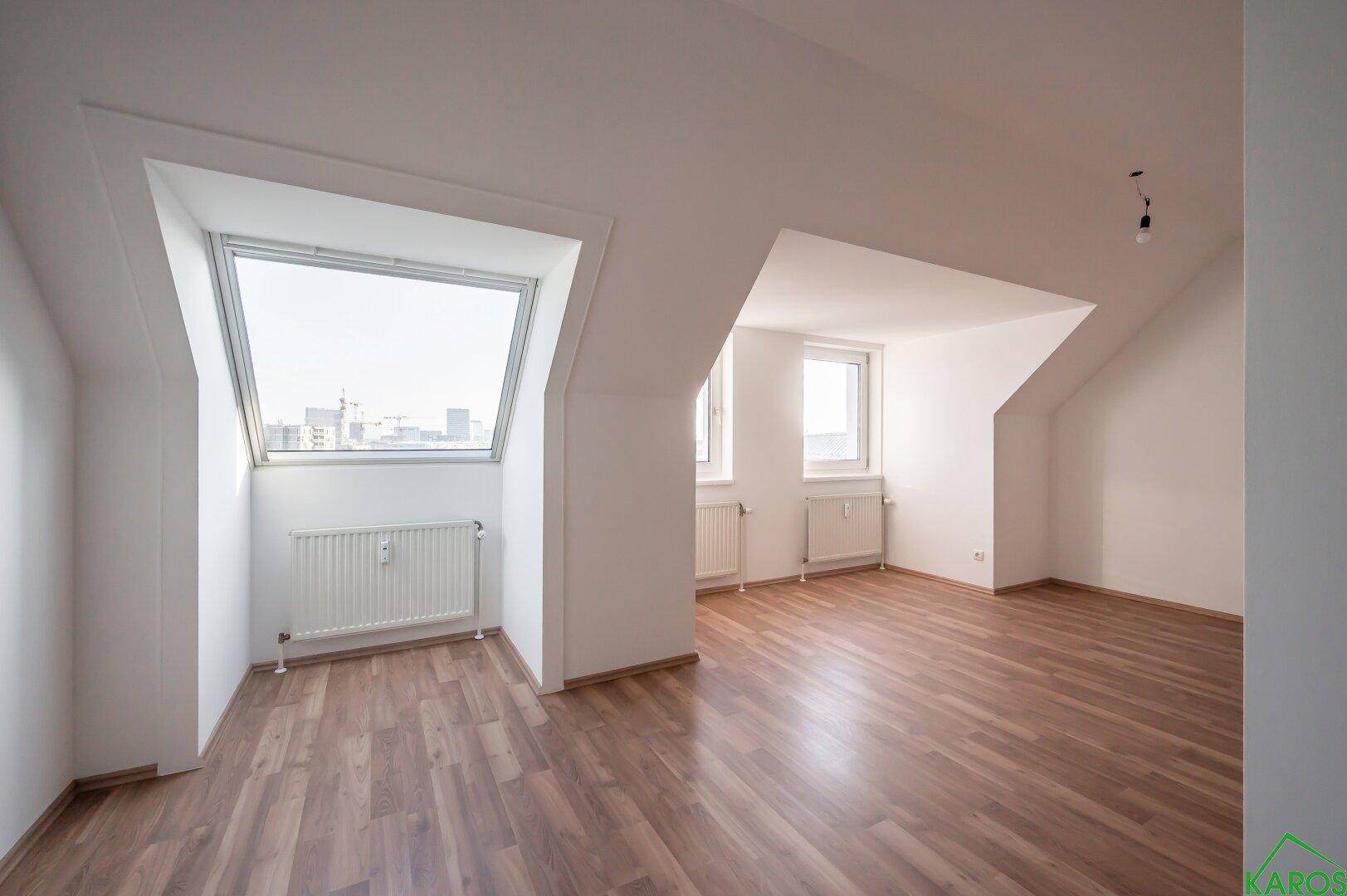 Geräumiges Dachzimmer mit Laminatboden, großen Dachfenstern und viel Tageslicht.