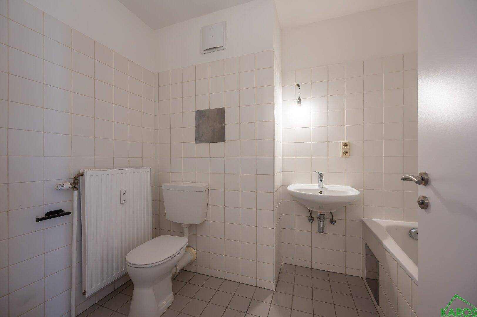 Helles Badezimmer mit WC, Waschbecken und Badewanne, komplett gefliest und gut gepflegt.