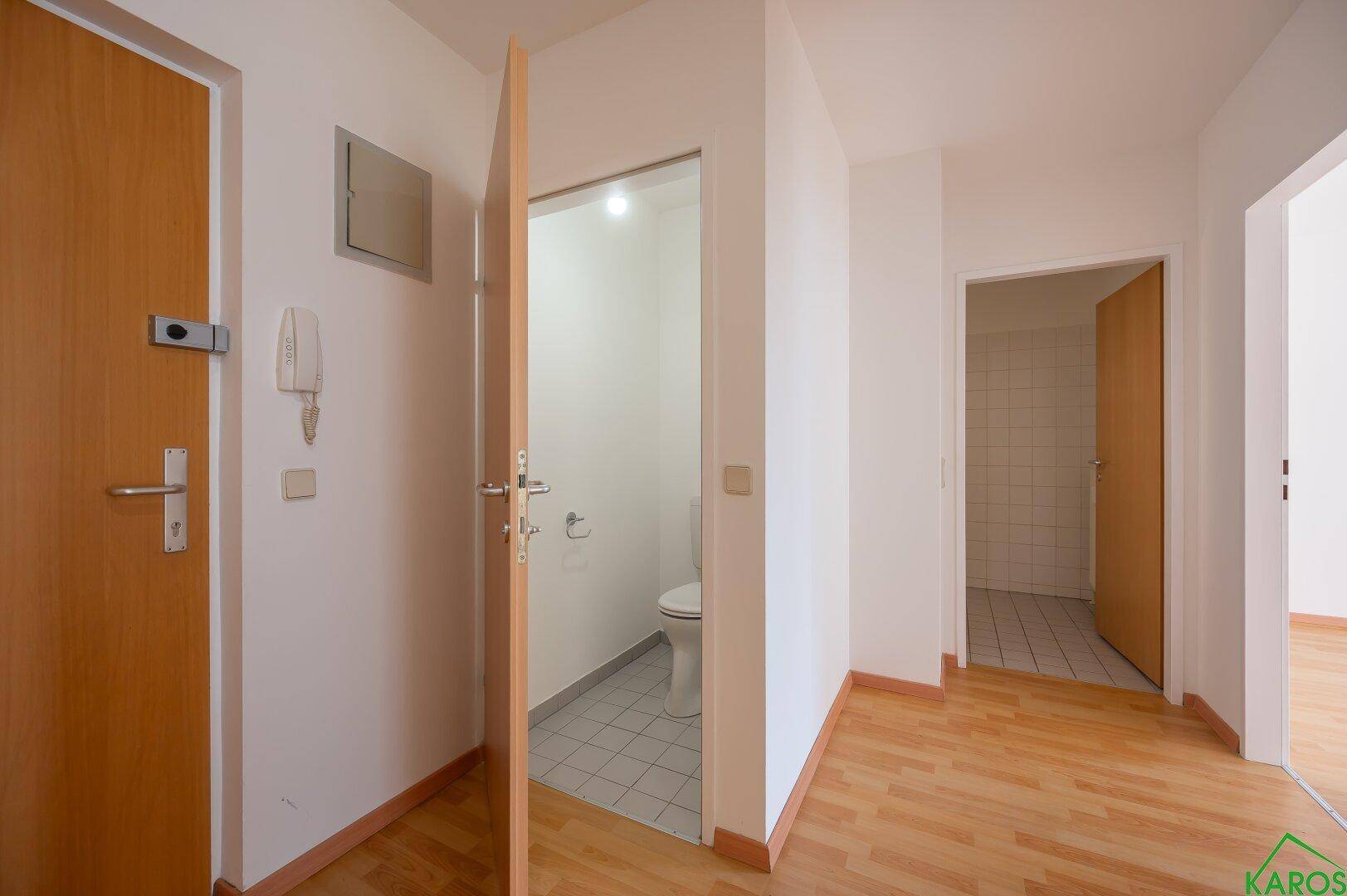 Flur mit Laminatboden und Zugang zu einem Gäste-WC, das Funktionalität und Komfort bietet.