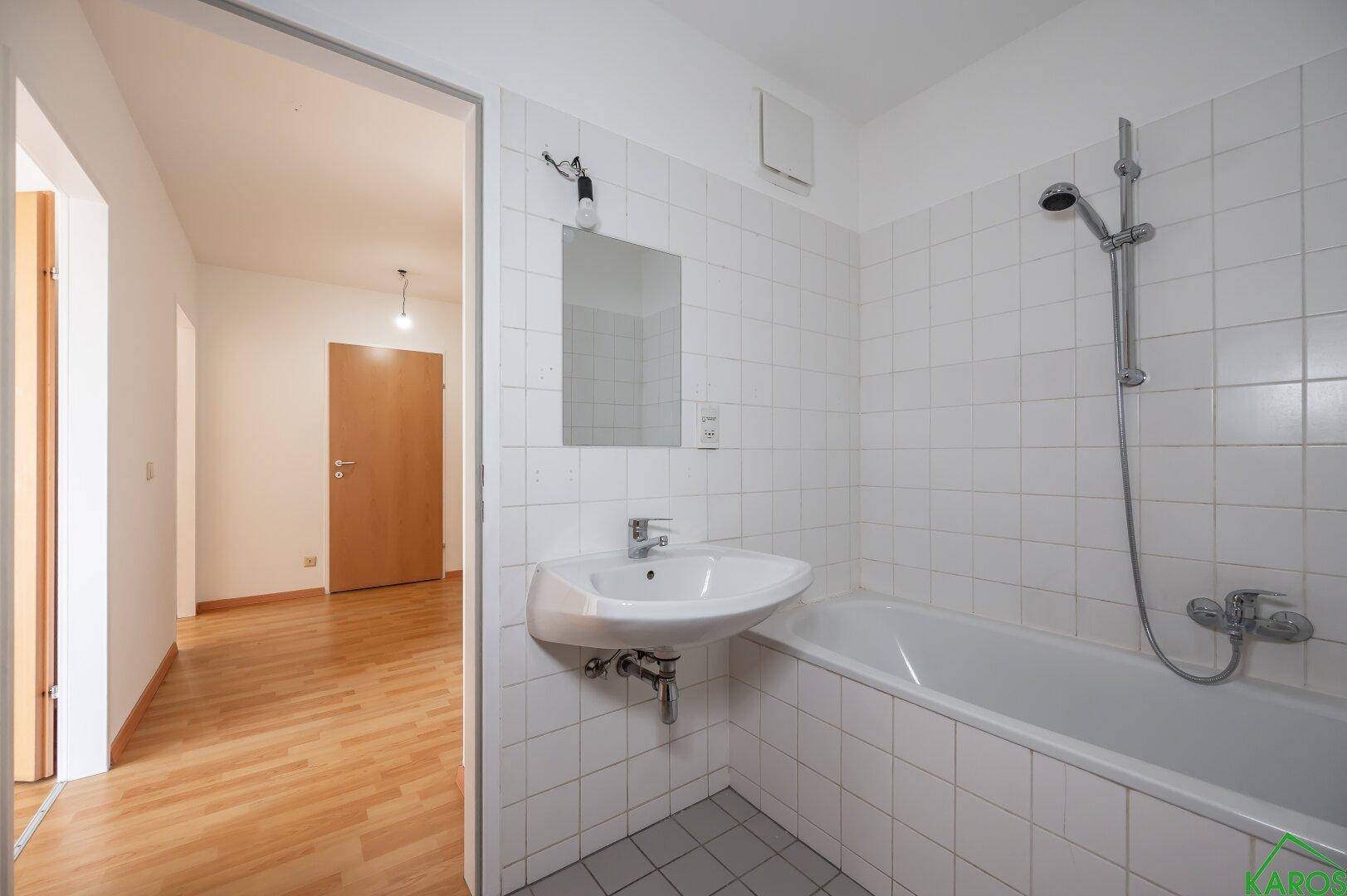 Helles Badezimmer mit Waschbecken, Badewanne und weißen Fliesen, das einen gepflegten Eindruck macht.