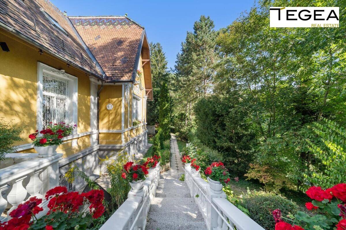 Geschwungener Treppenaufgang im Garten, gesäumt von roten Blumen und üppigem Grün.
