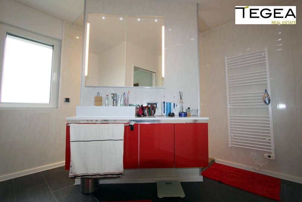 Modernes Badezimmer mit rotem Waschtischunterschrank, Spiegelschrank und Fenster.