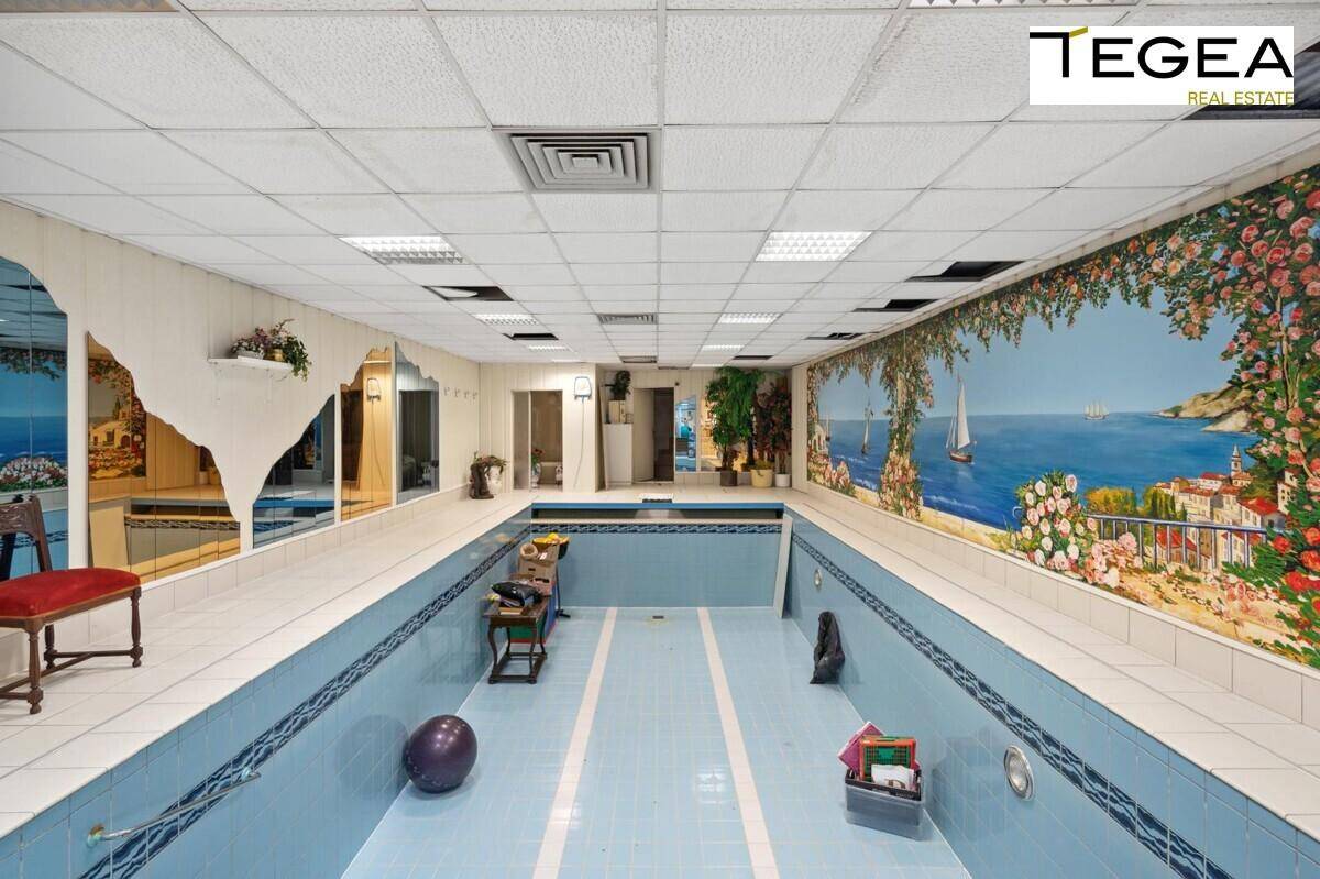 Großer Innenpool mit blauen Fliesen und Wandgemälden, ideal für Entspannung und Sport.
