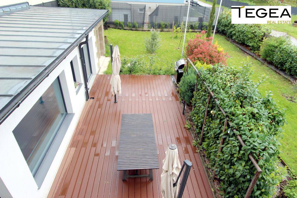 Holzterrasse mit Esstisch, Sonnenschirmen und Blick auf den Garten.
