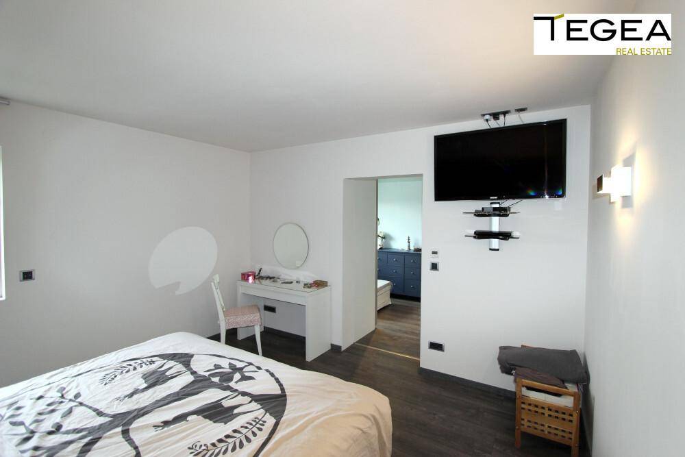 Schlafzimmer mit Doppelbett, Schminktisch und Fernseher an der Wand.