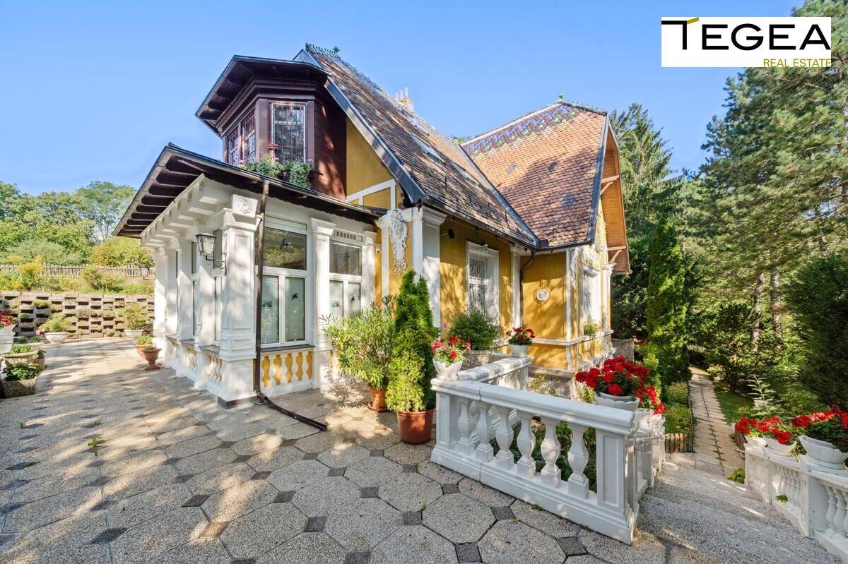 Seitenansicht der historischen Villa mit gelber Fassade, weißen Verzierungen und Zugang zum Garten.