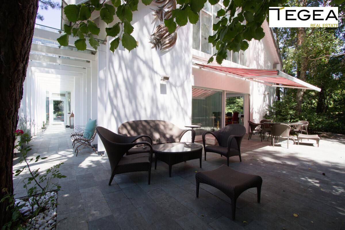 Gemütliche Terrasse mit Rattanmöbeln und Blick auf den Garten, ideal für entspannte Stunden im Freien.
