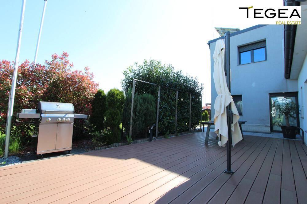 Sonniger Terrassenbereich mit großem Grill und viel Platz für Outdoor-Aktivitäten.