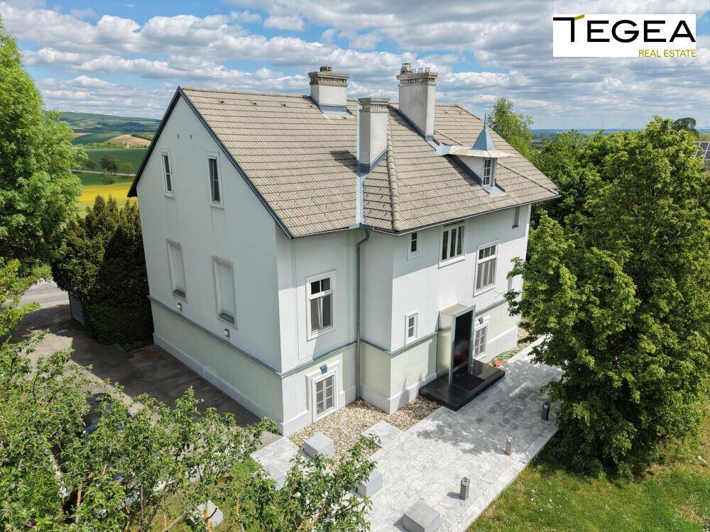 Ansicht der Hausfassade mit gepflastertem Eingangsbereich und weitem Blick über die Landschaft.