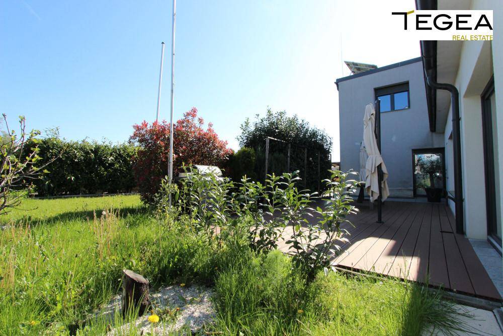 Garten mit Rasenfläche und angrenzender Holzterrasse, ideal für entspannte Stunden im Freien.