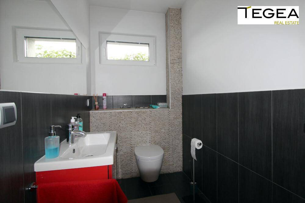 Modernes Gäste-WC mit dunklen Fliesen, Waschbecken und Fenster für Tageslicht.
