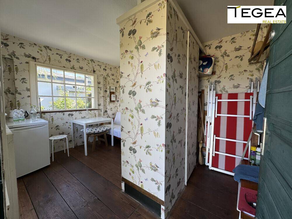 Gemütlicher Raum mit Esstisch, gemusterten Tapeten und Blick durch die Fenster.