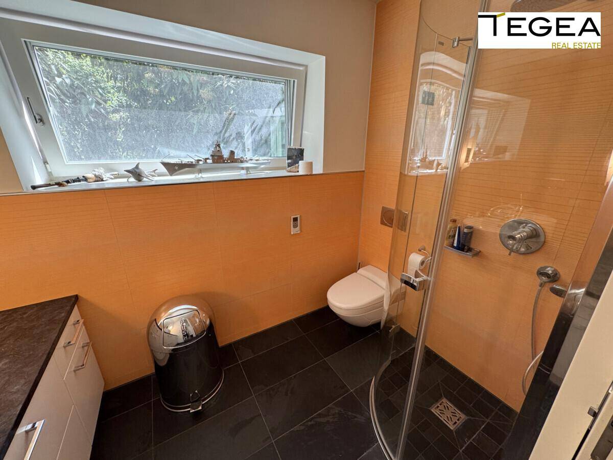Modernes Badezimmer mit begehbarer Dusche, orangefarbenen Fliesen und Fenster.