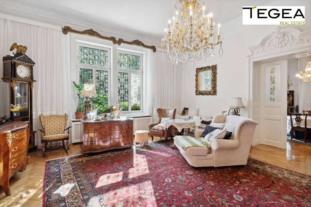 Elegantes Wohnzimmer mit Kronleuchter, Parkettboden und antiken Möbeln, lichtdurchflutet.