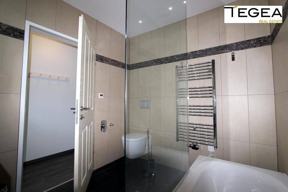 Modernes Badezimmer mit Wand-WC, Duschbereich und beheiztem Handtuchhalter.