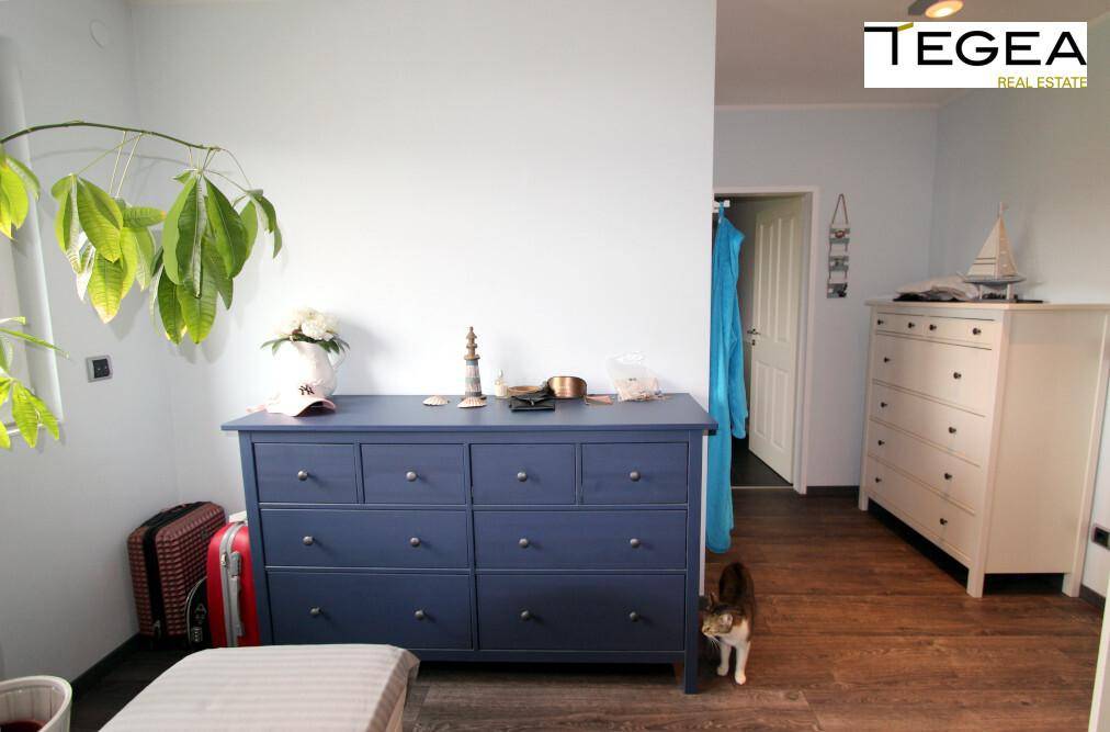 Helles Schlafzimmer mit Holzboden, blauer Kommode und Pflanzen.