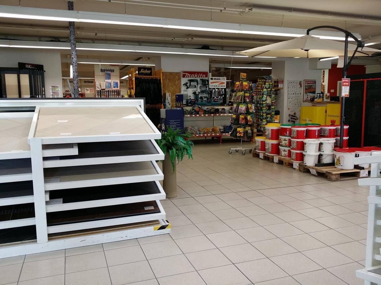 Heller Verkaufsraum mit Fliesenböden, Ausstellungsflächen für Baumaterialien und verschiedenen Produkten.