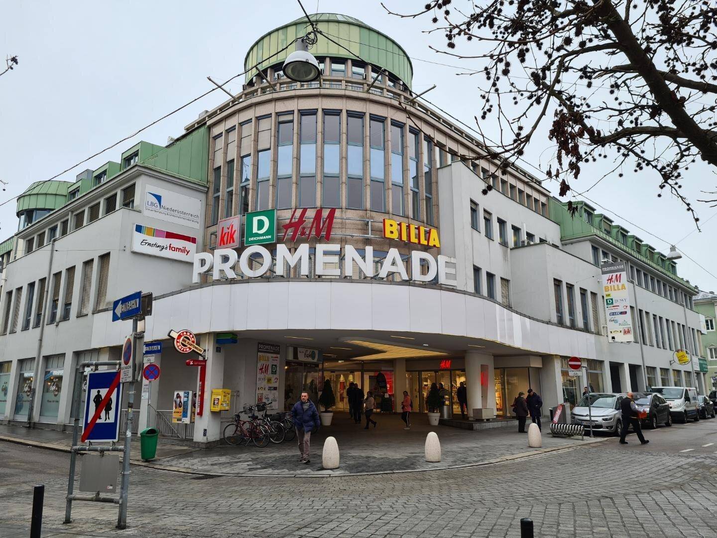 Gesamtansicht eines modernen Einkaufszentrums mit mehreren Geschäften und einer markanten Kuppel.