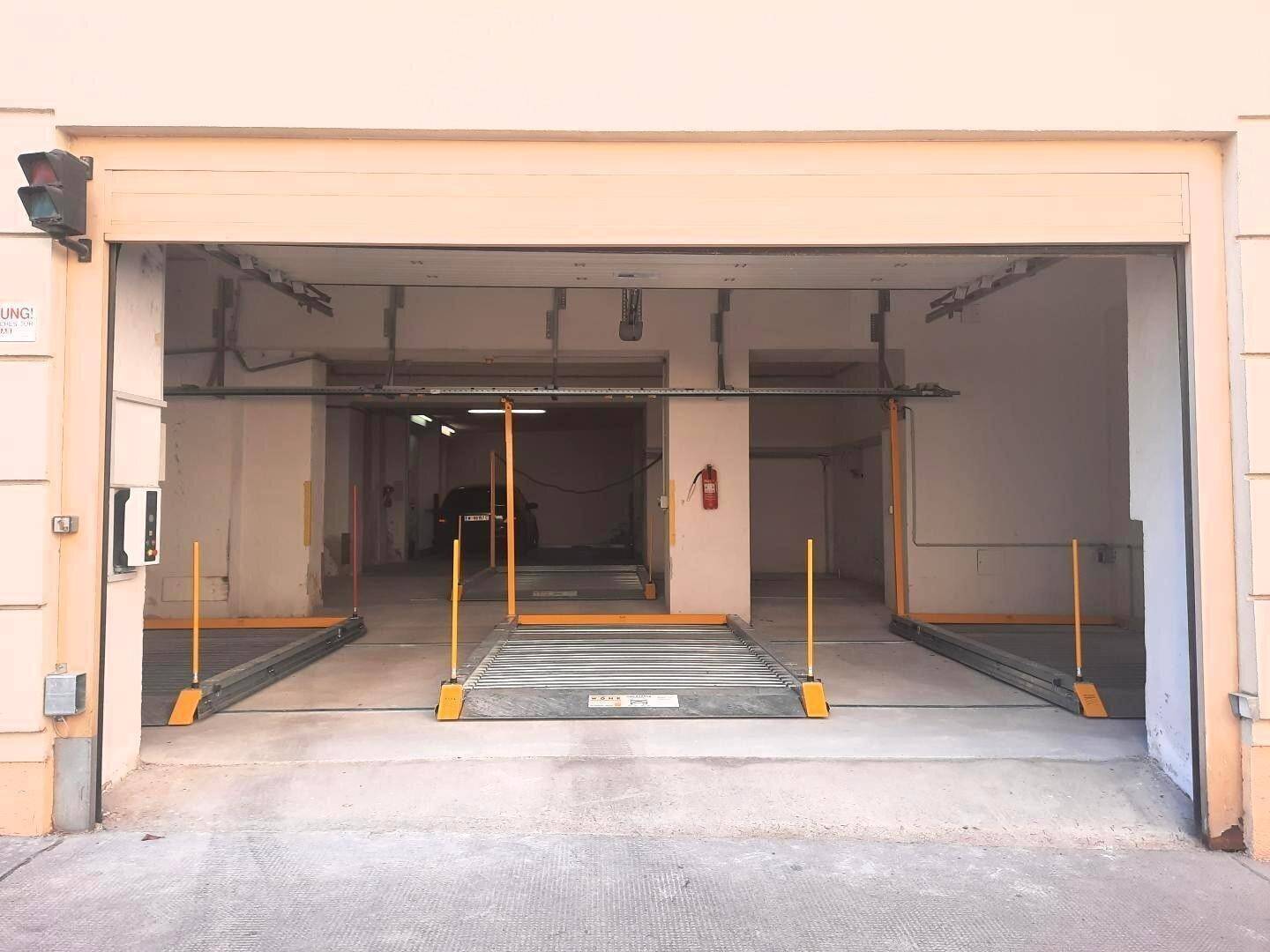 Außenansicht der Tiefgarageneinfahrt mit geöffnetem Tor und Verkehrsampel.