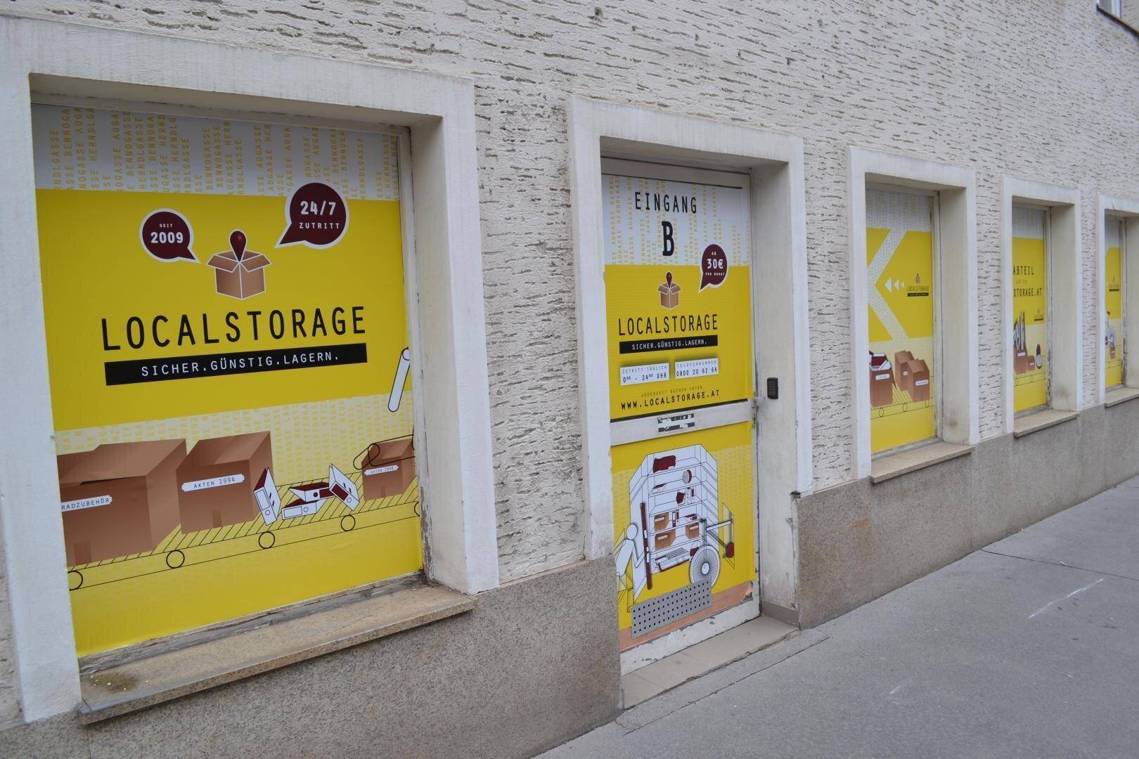 Fassade eines Gebäudes mit mehreren Fenstern und Türen, die mit auffälligen gelben Werbeaufklebern für Lagerlösungen versehen sind.
