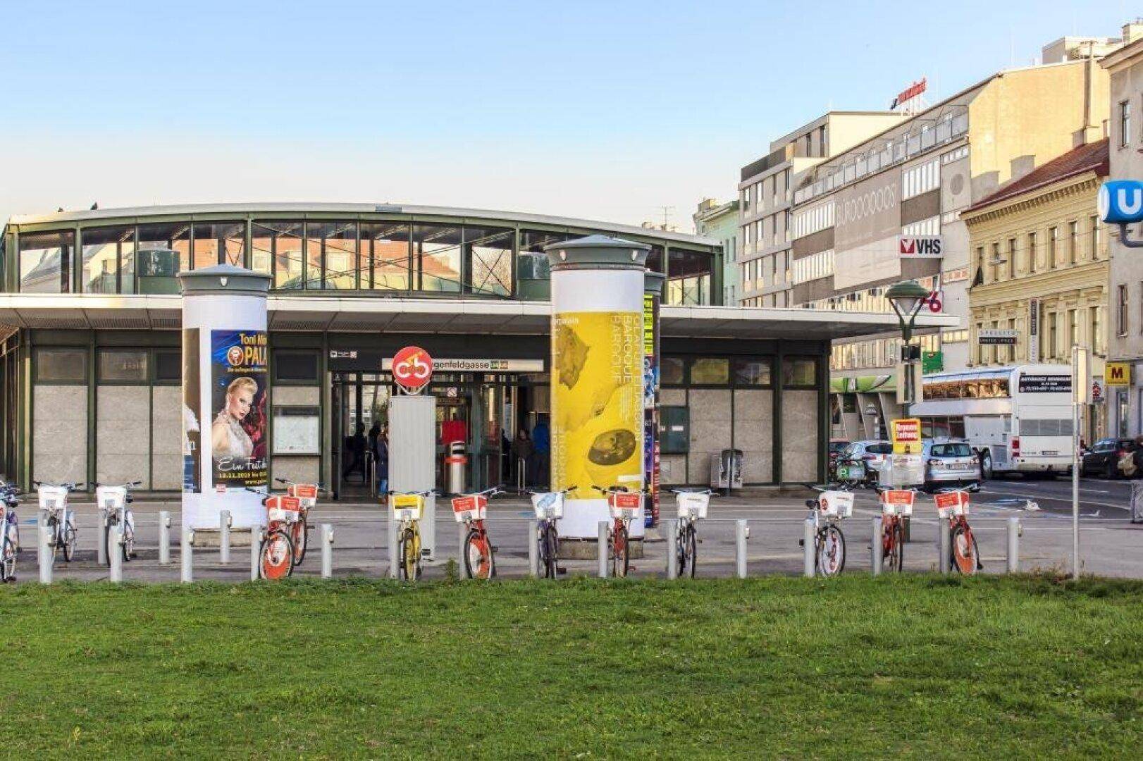 Eingang einer U-Bahn-Station mit Fahrradverleih im Vordergrund, umgeben von städtischer Architektur.