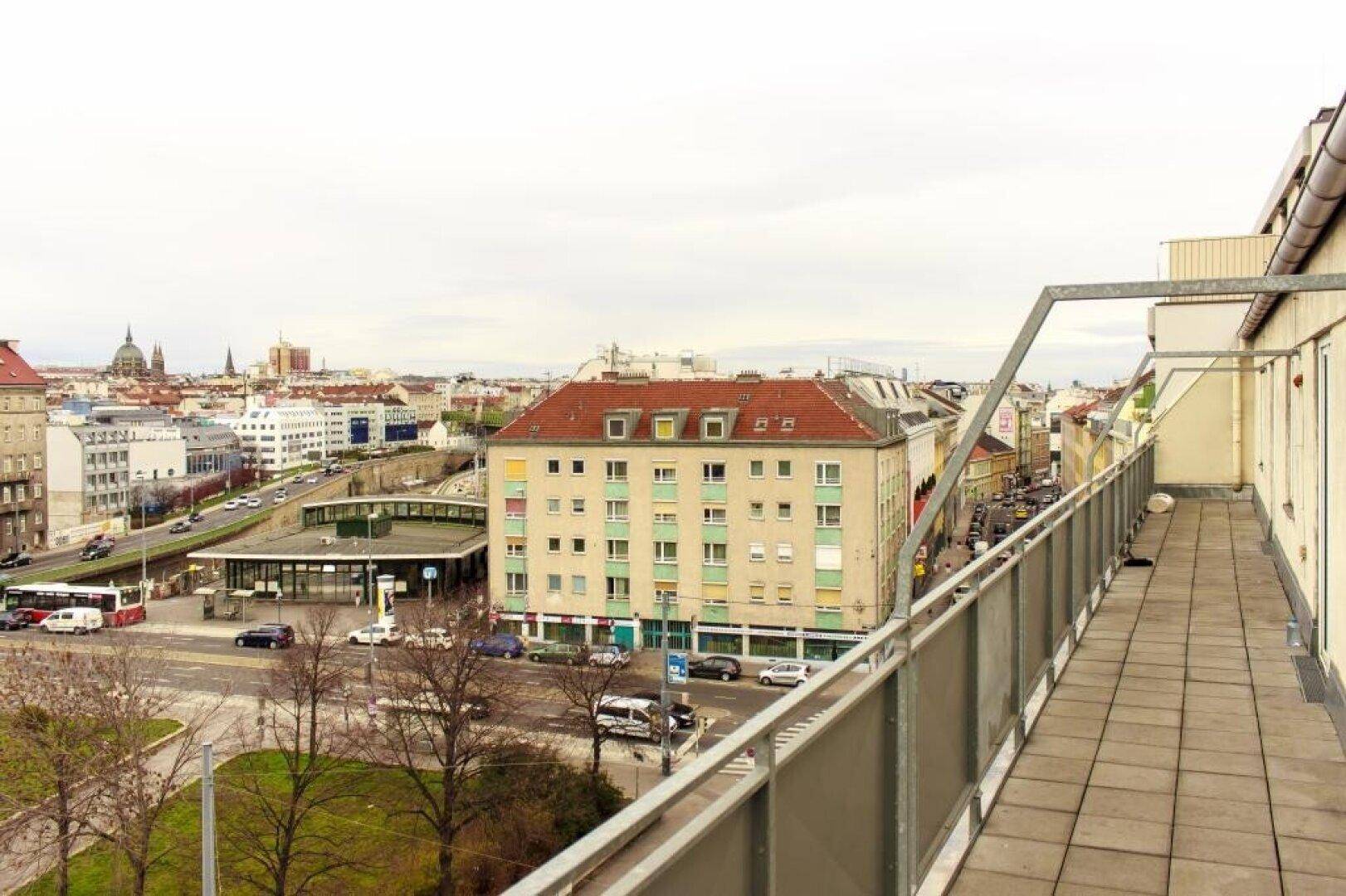 Langer Balkon mit Fliesenboden und Metallgeländer, bietet einen weiten Blick über die Stadt.