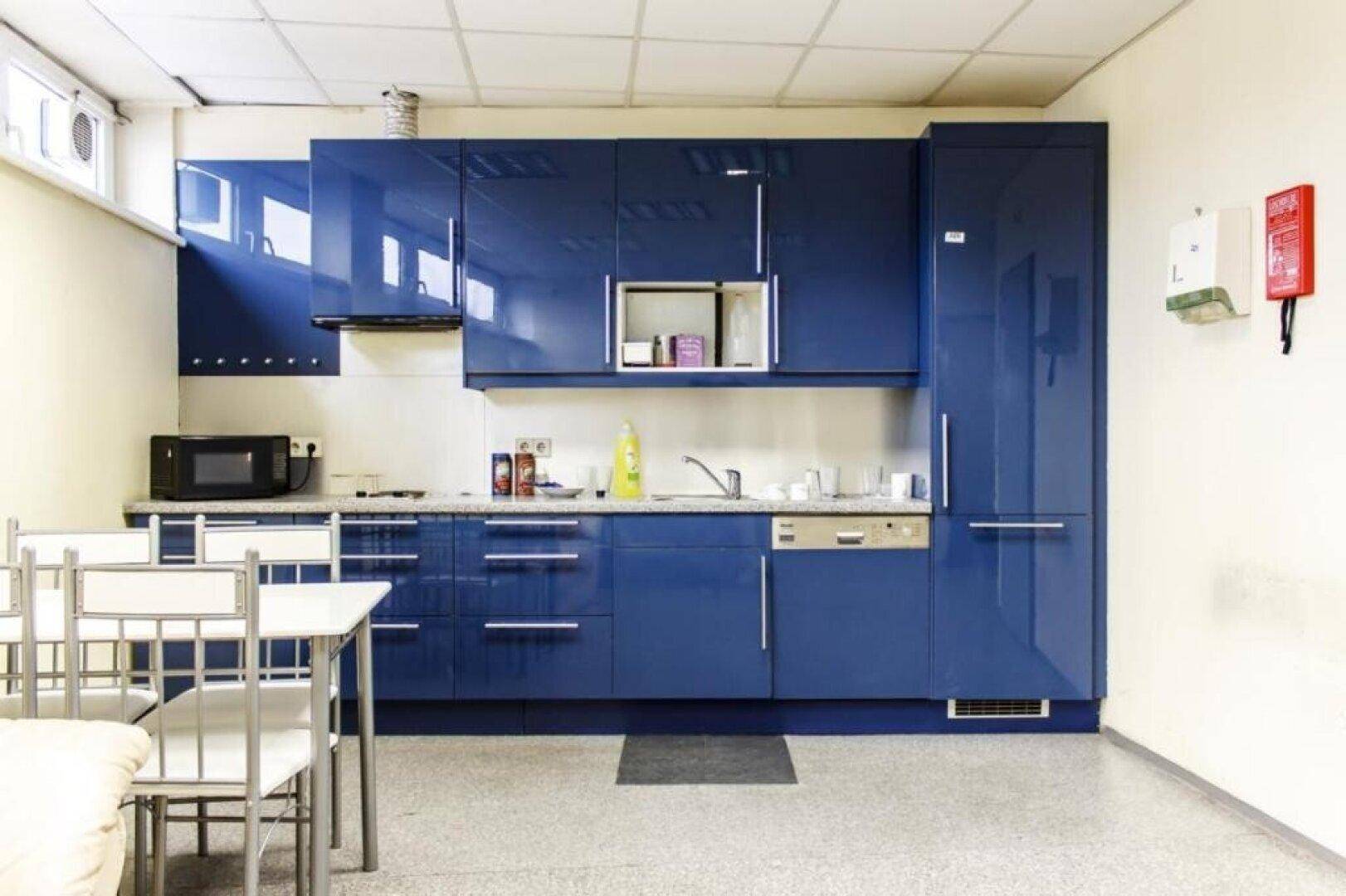 Moderne Küche mit glänzenden blauen Schränken, integrierten Geräten und Essbereich.