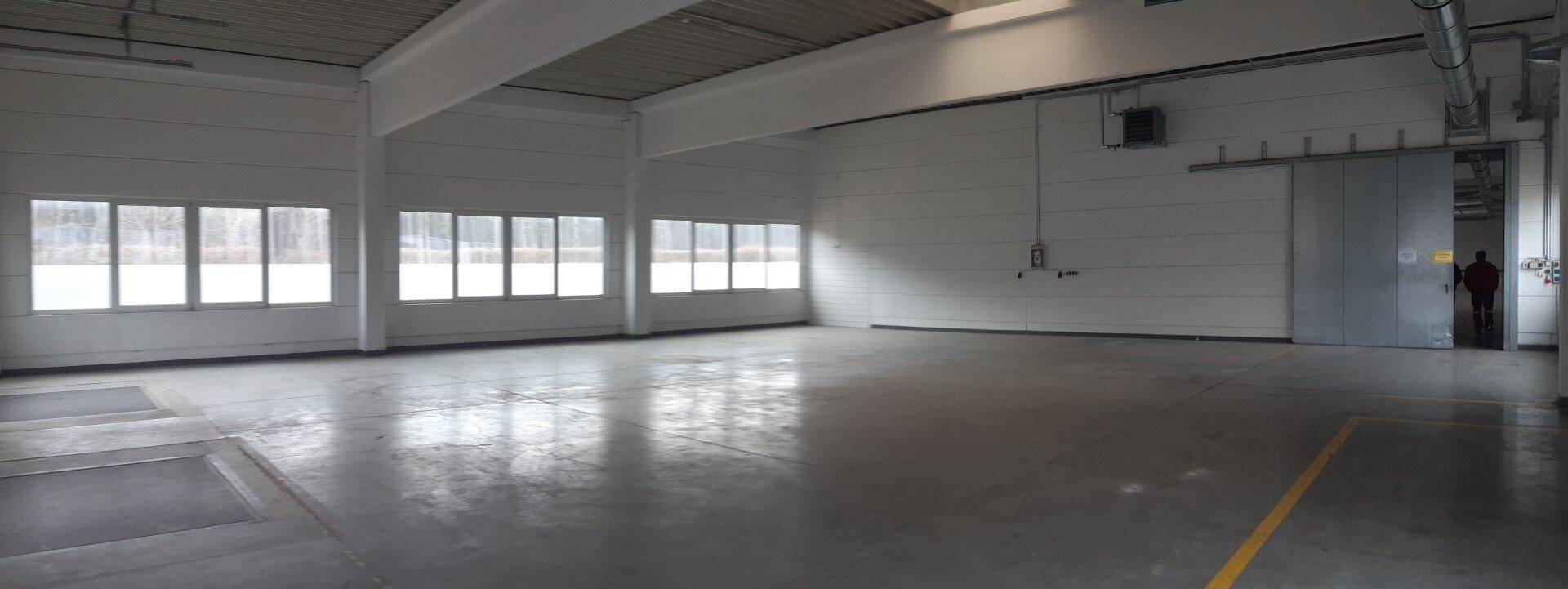 Geräumiger Industrieraum mit einer langen Fensterfront und einer großen Schiebetür, die viel Licht hereinlässt.