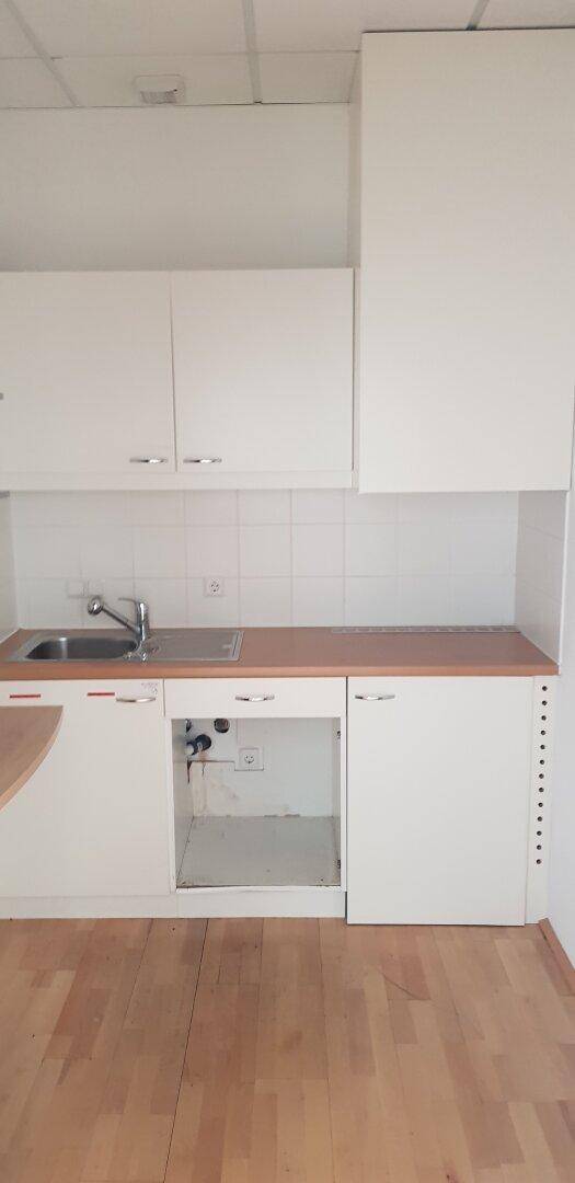 Kleine, weiße Küchenzeile mit Spüle und Holz-Arbeitsplatte, ideal für ein Büro.
