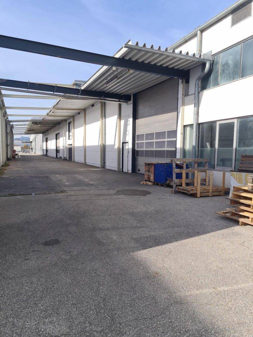 Außenansicht einer modernen Lagerhalle mit Rolltoren und Zufahrtsbereich für Lieferungen.