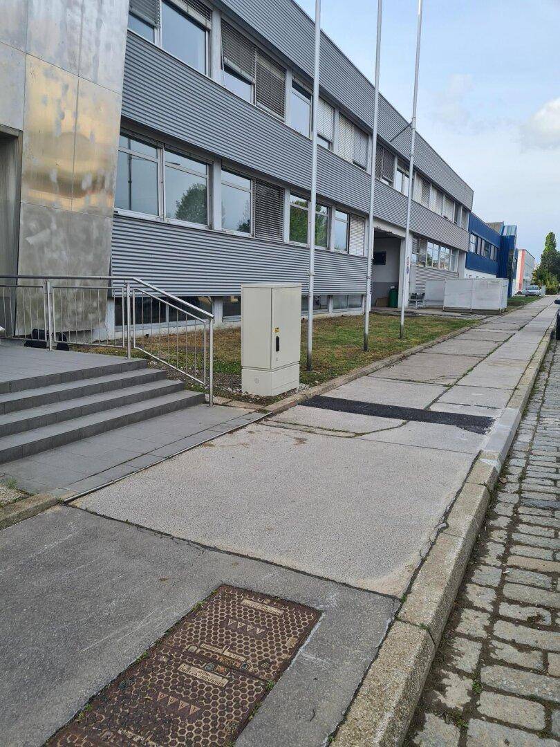 Detailansicht der Gebäudefassade mit Eingangsbereich, Treppe und Gehweg.