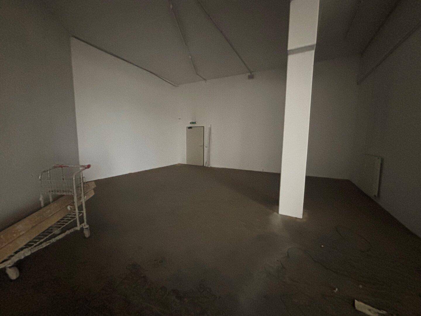 Leerer Gewerberaum mit Betonboden und einer tragenden Säule, bereit für die zukünftige Nutzung.