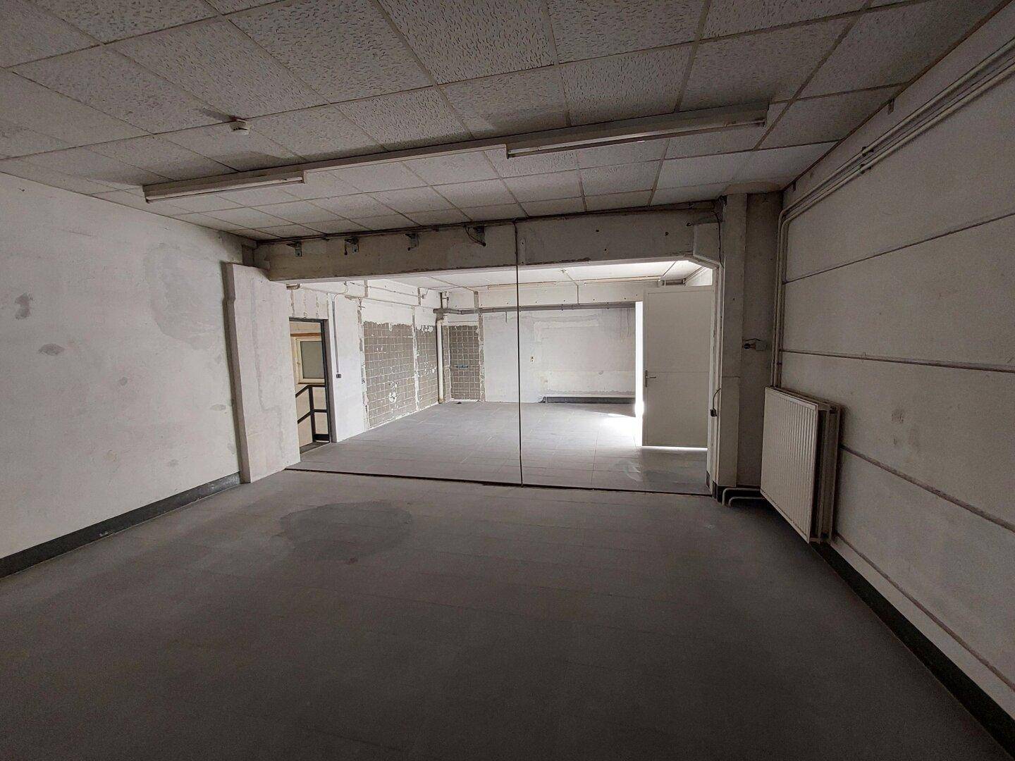 Großer, leerer Gewerberaum mit Betonboden und Deckenleuchten, bereit für die individuelle Nutzung.
